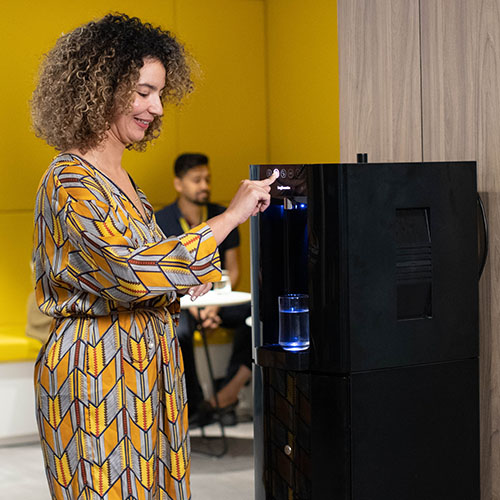 woman dispensing water from an Active B&O E6 floor standing water cooler in black in an office environment
