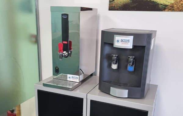 A 1500l table top water boiler next to a table top version of the AA3300 water cooler in an office environment