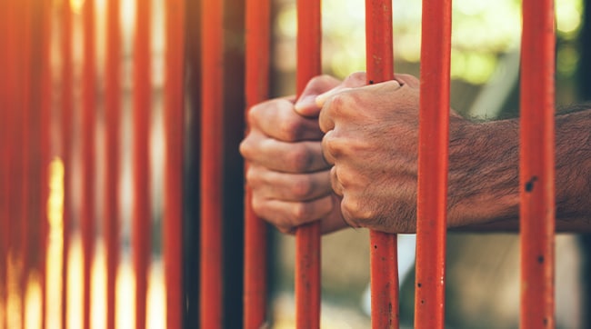 hands holding prison bars representing the prison in Northallerton, North Yorkshire.