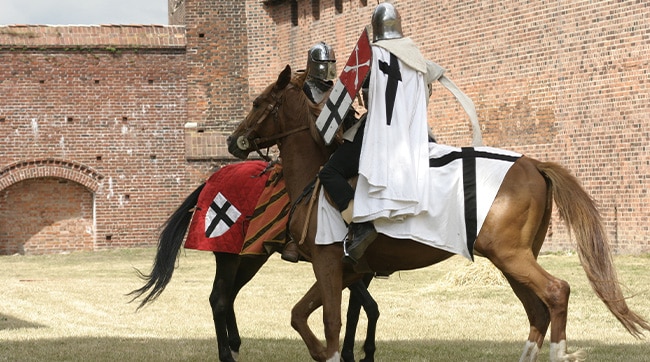 Two knights on horseback in front of a medieval castle