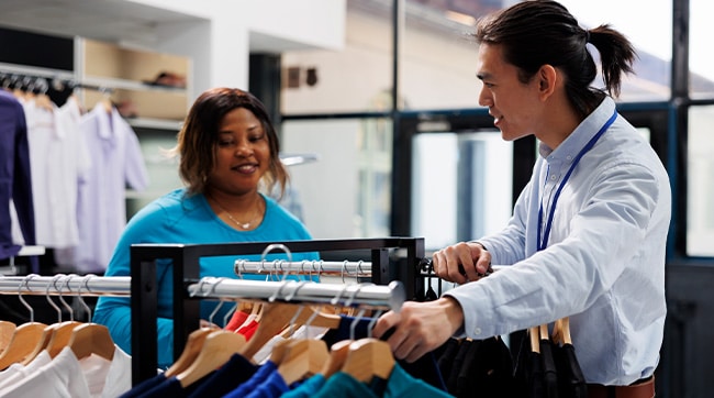 a clothes shop with shop assistant showing clothing to a customer