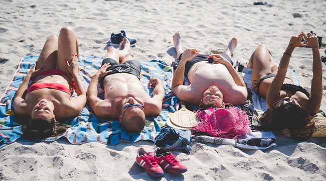4 people sunbathing on a beach